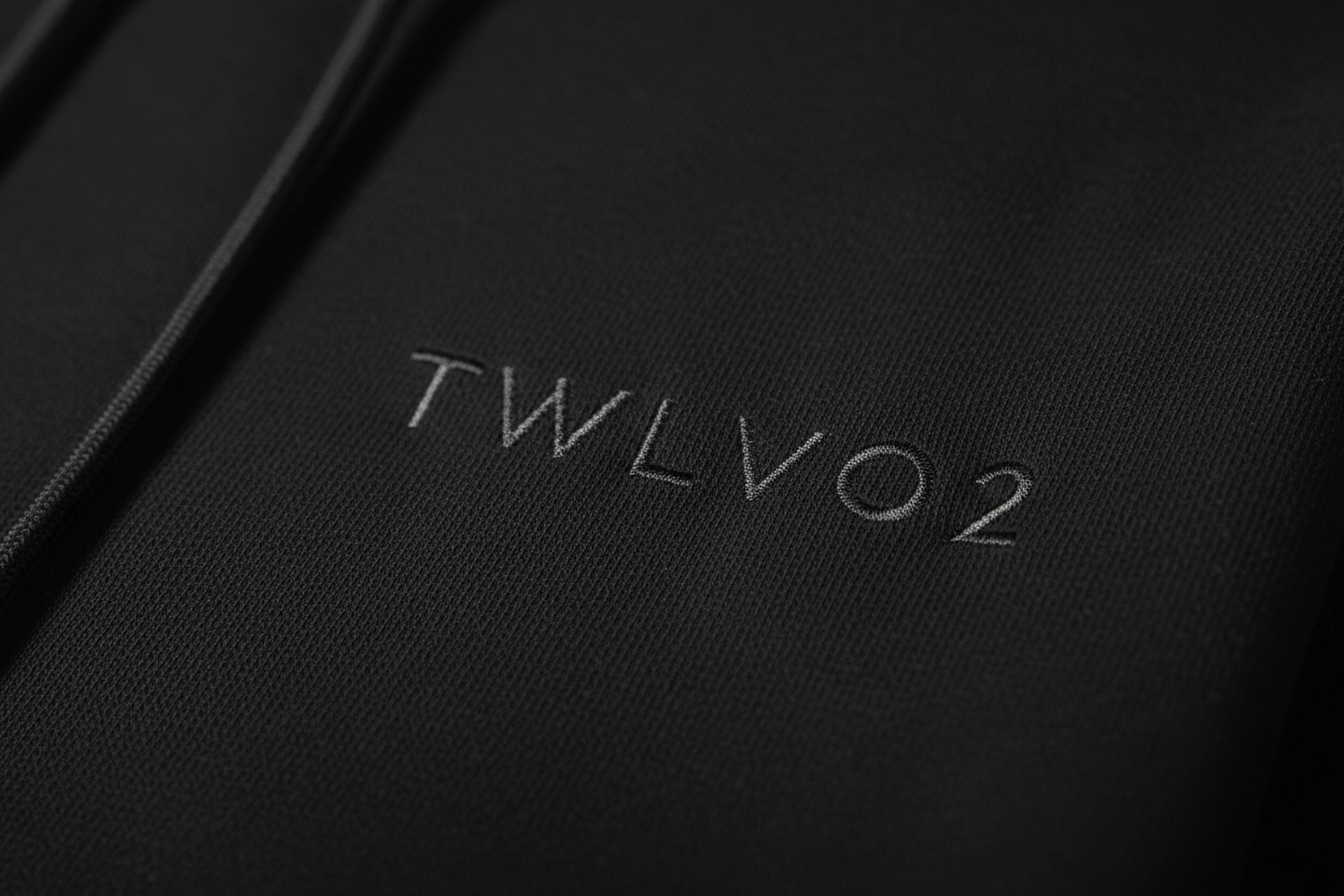 Close-up of embroidered TWLV02 logo on black hoodie fabric
